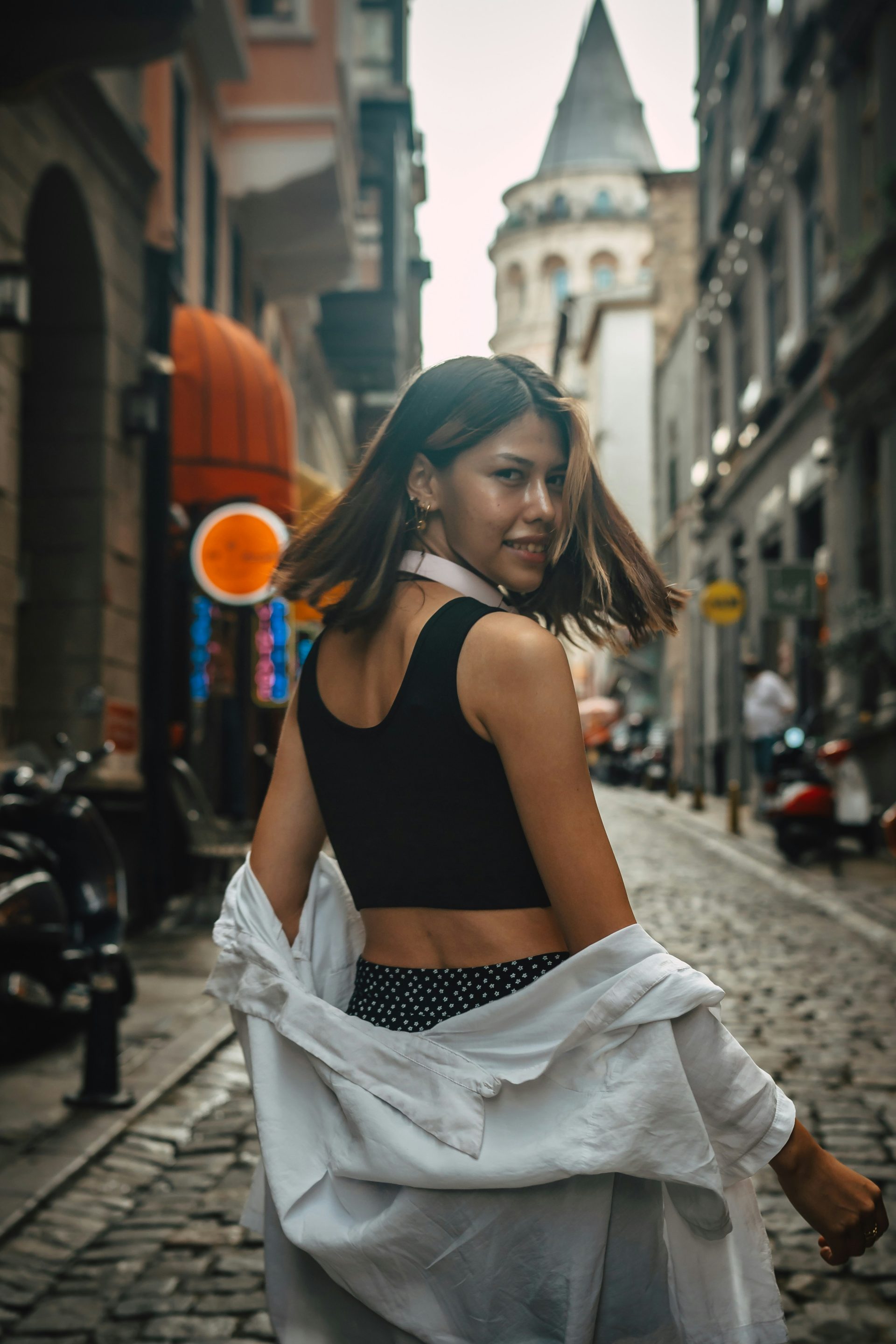 A woman walking down a street next to tall buildings