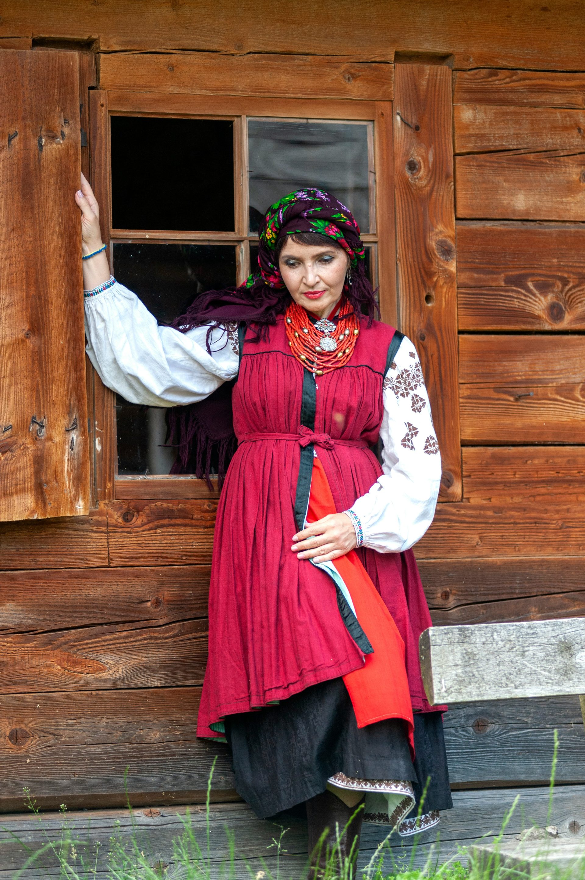 a woman in a red dress standing by a window